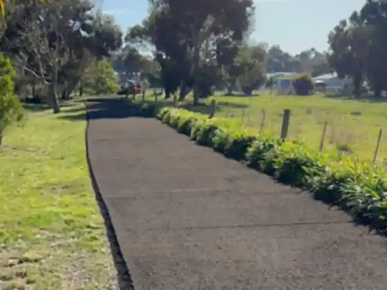 Sealed asphalt driveway running beside a planted garden border