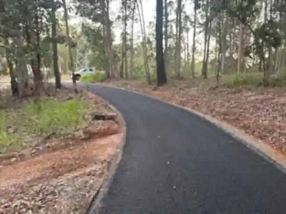 Curved asphalt access track sealed through bushland