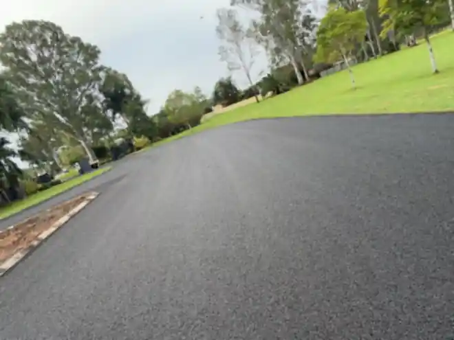 Wide asphalt driveway and turning circle finished beside a lawn